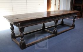 A 17th century style oak refectory table, with planked top and foliate carved frieze, on turned