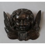 An early 16th century carved wood and painted gesso model of winged amorini bust, 5 x 6.25in.