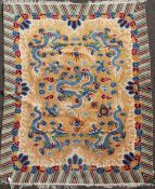 A Chinese carpet, the apricot field with five indigo dragons with a polychrome banded border, 10ft
