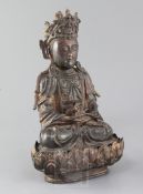 A Chinese lacquered bronze seated figure of Guanyin, possibly Ming dynasty, holding a ewer in both