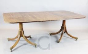 A George III style mahogany twin pillar dining table, the reeded rounded rectangular top with