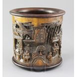 A Chinese bamboo brush pot, carved in high relief with figures amid pavilions with an inscription,