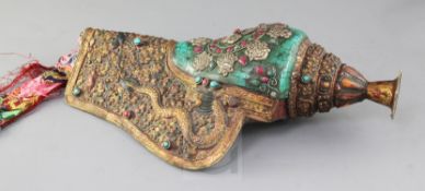 A Tibetan gilt copper gem set conch shell trumpet, with embossed dragons amid scrolls, polychrome