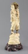 A Japanese walrus ivory okimono of a falconer, early 20th century, the figure standing on a rock,