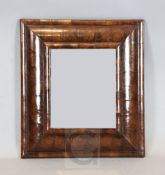 An early 18th century oyster veneered walnut cushion frame wall mirror, with bevelled glass plate,