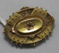 A late Victorian 15ct gold, ruby and seed pearl oval brooch, (2 seed pearls missing) with glazed