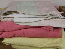 A rose pink and light pink reversible quilt, another reversible with yellow, the other mint green