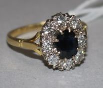 An 18ct gold, sapphire and diamond set oval cluster ring, size R.