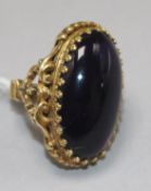 A large gold and cabochon amethyst set dress ring, with ornate carved shank and setting and