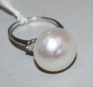 A 10ct white gold lareg baroque cultured pearl dress ring with diamond set shoulders, size O.