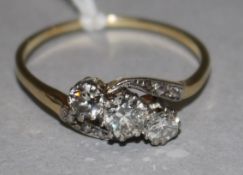 A gold and three stone diamond crossover ring, with diamond set shoulders, size W.
