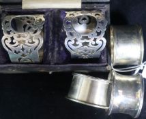 A cased pair of silver serviette rings and three others.