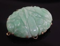 A gold mounted jadeite oval brooch, carved with fruit, 41mm.