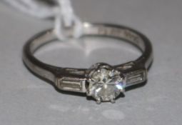 An 18ct white gold and platinum single stone diamond ring with baguette cut diamond set shoulders,