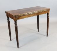 A Regency brass strung rosewood card table, with rounded rectangular folding top, on turned and