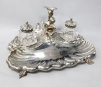 A late Victorian silver plated shell shaped inkstand, with two wells and central figural pen holder,