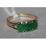 A 14ct gold three stone emerald ring, with diamond set shoulders, size L.