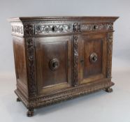 A 17th century Italian walnut credenza, carved on three sides with rolling tendrils, centred by a