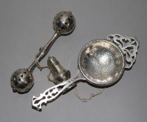 An Edwardian silver babies rattle, a George V silver tea strainer and a miniature silver pepper (3),