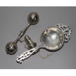 An Edwardian silver babies rattle, a George V silver tea strainer and a miniature silver pepper (3),