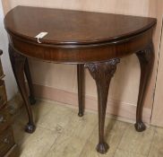 A 1930's carved mahogany demi-lune folding tea table, W.92cm