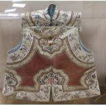 A Chinese embroidered silk and metal thread tunic, perspex case