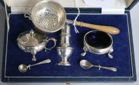 A 1950's cased silver three piece condiment set and a silver tea strainer with stand.