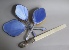 A silver and enamel three piece brush set and a silver handled ivory page turner.