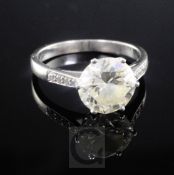 A white gold and single stone diamond ring with graduated diamond set shoulders, the round cut stone