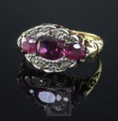 An early 20th century 18ct gold, ruby and diamond oval cluster ring, set with three rubies and