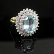 An 18ct gold, aquamarine and diamond oval dress ring, the central oval cut aquamarine bordered by