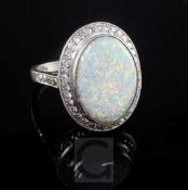 An 18ct gold and platinum, white opal and diamond set oval dress ring, with diamond set shoulders,