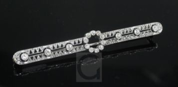 A 1920's white gold and diamond set pierced openwork bar brooch, 68mm.