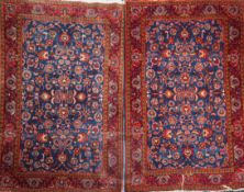 A pair of Persian red and blue ground rugs, with foliate scroll decoration and three row border, 6ft