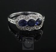 A modern platinum, sapphire and diamond triple cluster ring, with diamond set shoulders, size M.