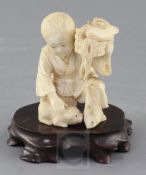 A Japanese ivory okimono of a boy with a dog, Meiji period, the boy kneeling and holding a basket of