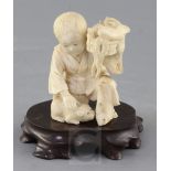 A Japanese ivory okimono of a boy with a dog, Meiji period, the boy kneeling and holding a basket of