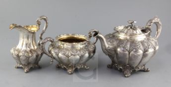 An early Victorian silver three piece tea set by The Barnards, of melon form, with leaf and flower