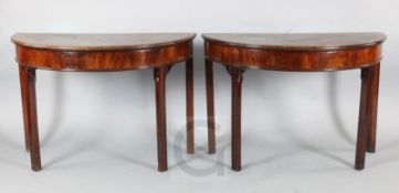 A pair of George III mahogany demi lune side tables, formerly dining table ends, with moulded