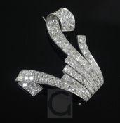 A platinum and diamond encrusted clip brooch, of scrolling design and set with round cut stones,