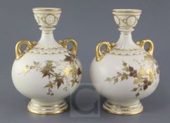 A pair of Royal Worcester ivory ground twin handled vases, date code for 1887, each gilt decorated