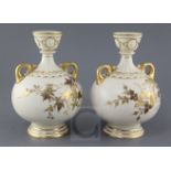 A pair of Royal Worcester ivory ground twin handled vases, date code for 1887, each gilt decorated