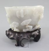 A Chinese greyish-white jade cup or brushwasher, carved in high relief with a chi-dragon, a bat