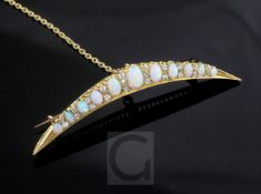 A Victorian style gold, graduated white opal and diamond set crescent brooch, with safety chain,