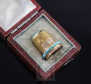 An early 20th century gold, green hardstone and turquoise set thimble, in gilt tooled red leather