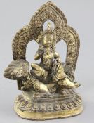 A Tibetan gilt bronze figure of Vaishravana, seated on a lion holding a mongoose on a lotus petalled