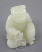 A Chinese pale celadon jade tiger-headed figure of a man, 18th / 19th century., seated and holding a