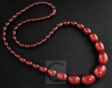 A single strand graduated simulated oval cherry amber bead necklace, gross 73 grams, 76cm.