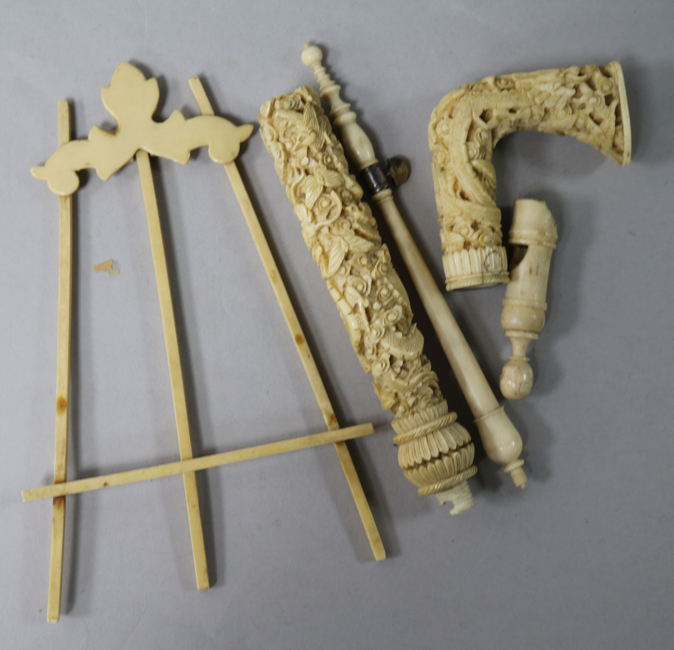 A carved ivory handle, a miniature ivory easel and other handles