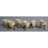 A set of six ivory egg cups, modelled as half egg shells of three chick leg supports, (one a.f.),